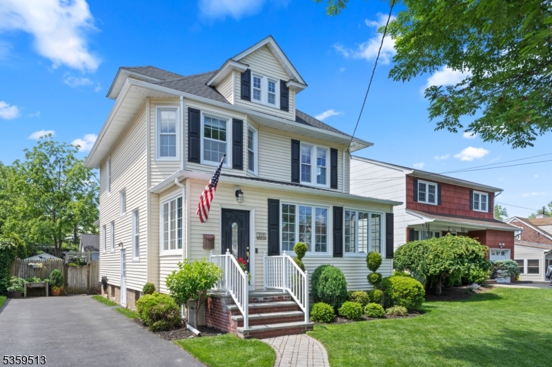 Updated 4-bedroom colonial home in Westfield NJ with white siding, black shutters, landscaped front yard, and inviting front porch with American flag