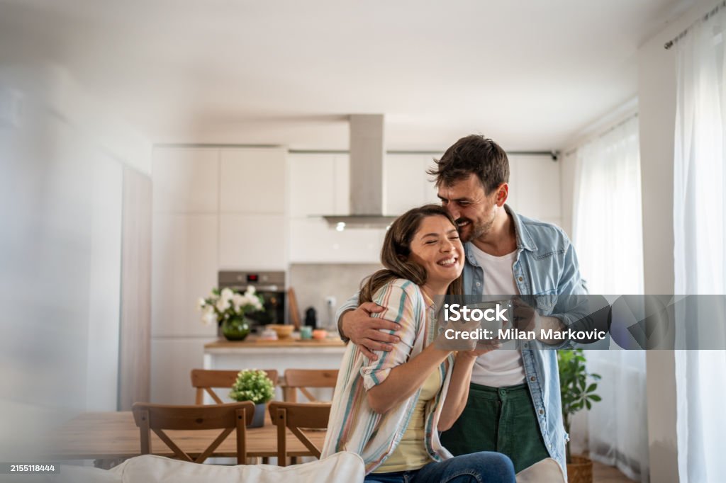Happy first-time homebuyers embracing in a bright, modern kitchen in their new home